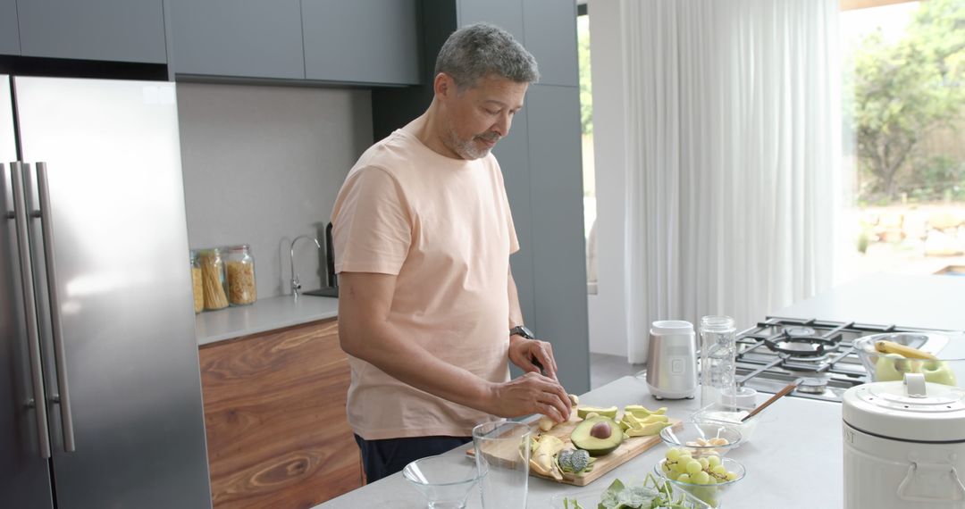 Middle-aged man preparing healthy meal in modern kitchen - Free Images, Stock Photos and Pictures on Pikwizard.com