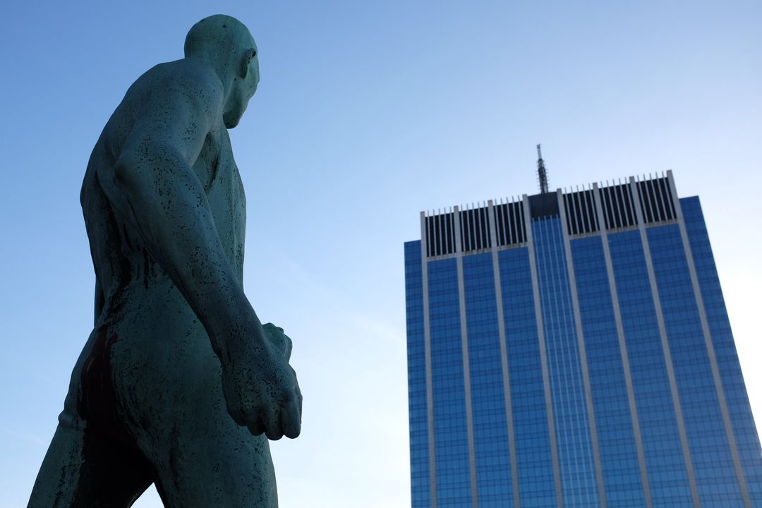 Modern Skyscraper Seen from Below with Artistic Statue in Foreground