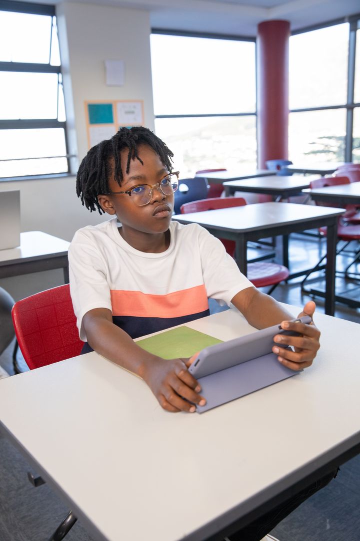 Teen Student Holding Tablet Sunlit School Classroom