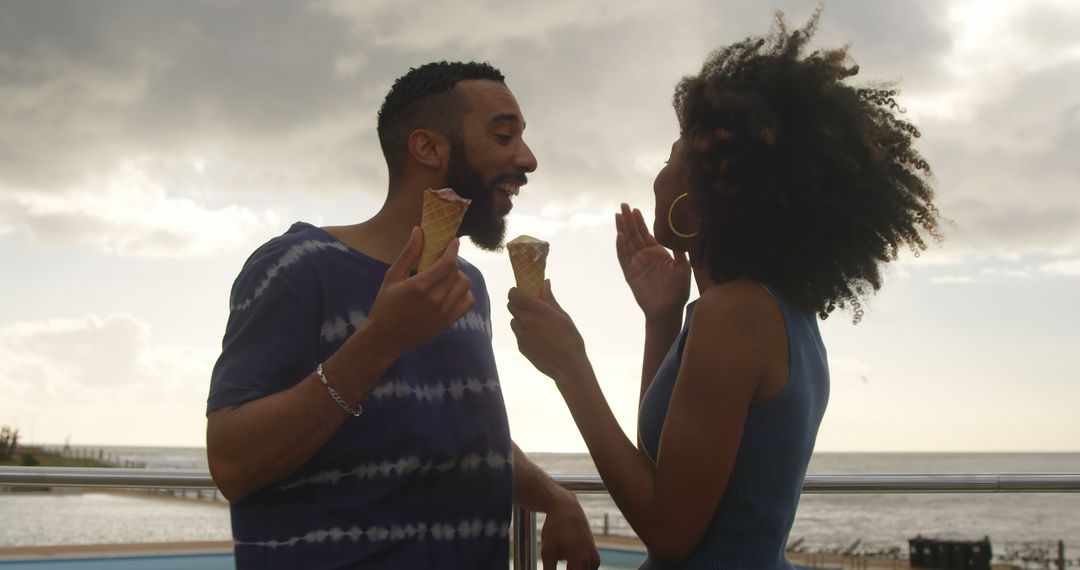 Happy couple enjoying ice cream by the beach at sunset - Free Images, Stock Photos and Pictures on Pikwizard.com