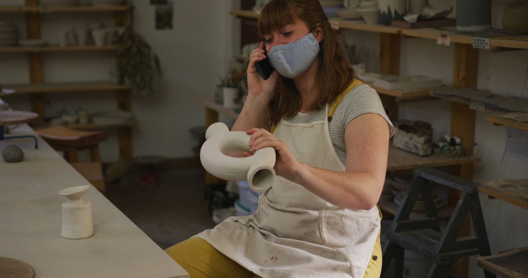 Female Ceramic Artist Wearing Mask and Talking on Phone in Studio - Free Images, Stock Photos and Pictures on Pikwizard.com