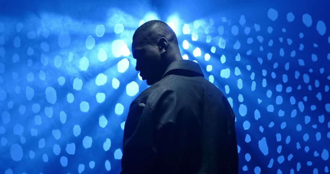 Man on Stage with Blue Lighting and Hazy Atmosphere