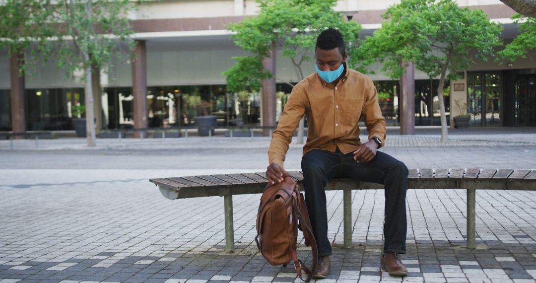 Young Man Wearing Mask Sitting on Bench in Urban Area - Free Images, Stock Photos and Pictures on Pikwizard.com