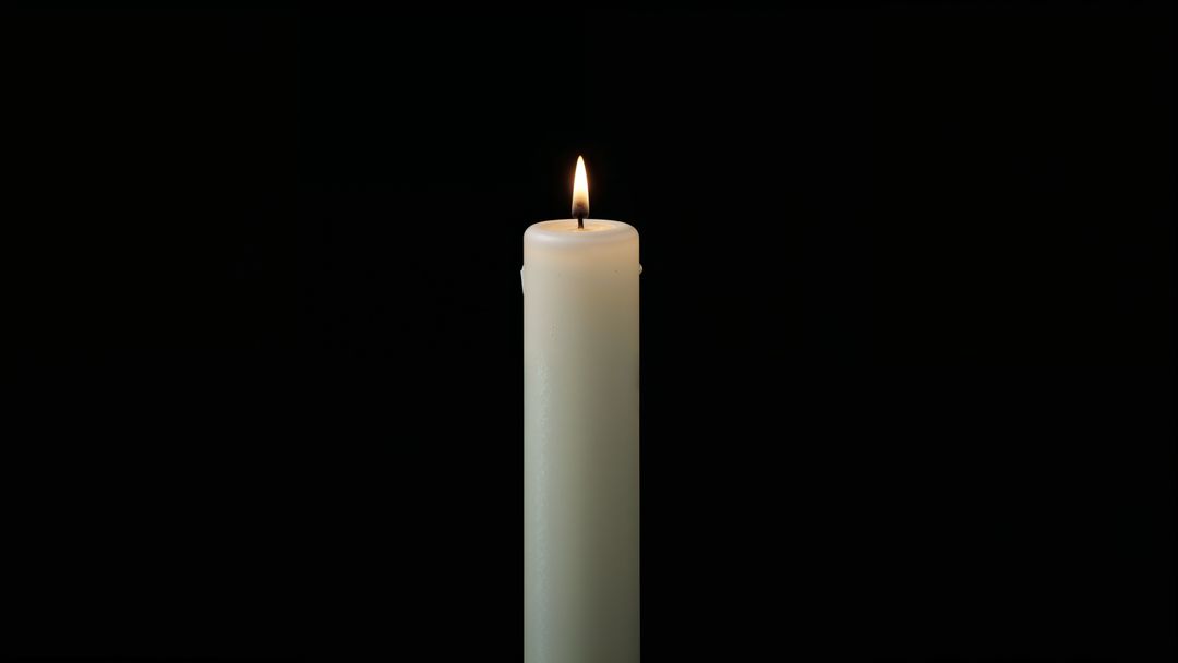 Flickering white candle against dark background for condolences