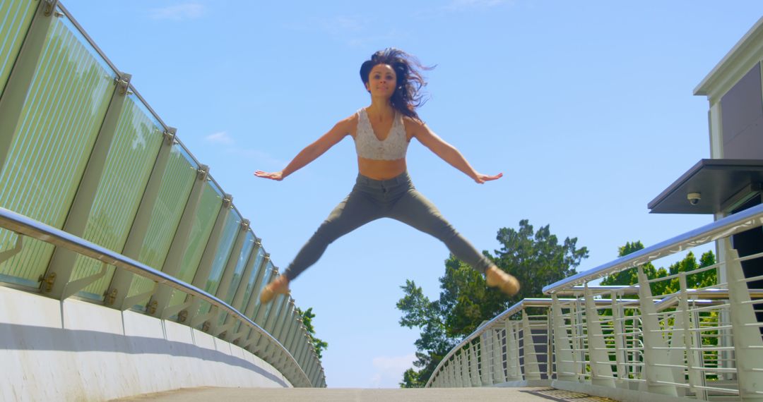 Confident Woman Performing Jump on Urban Bridge - Free Images, Stock Photos and Pictures on Pikwizard.com