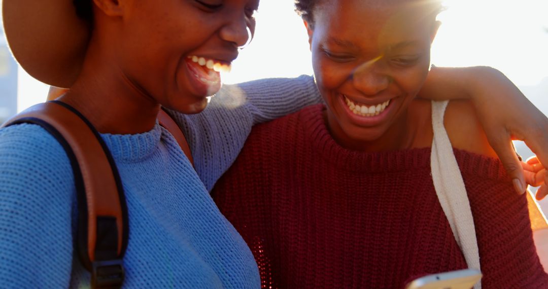 African American Twins Joyfully Sharing Mobile Moment in Cityscape