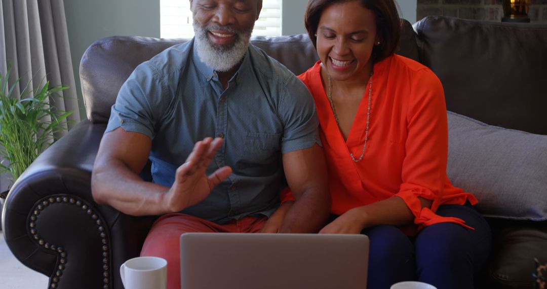 Joyful Senior Couple Video Calling with Laptop and Coffee at Home