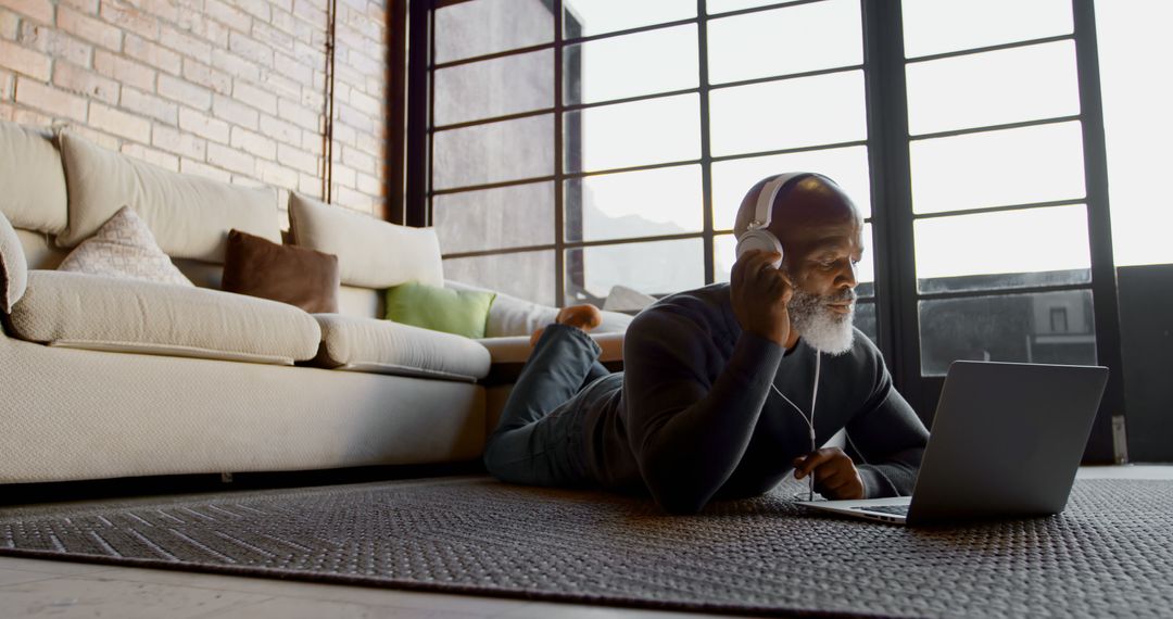 Senior Man Relaxing at Home Using Laptop and Headphones - Free Images, Stock Photos and Pictures on Pikwizard.com