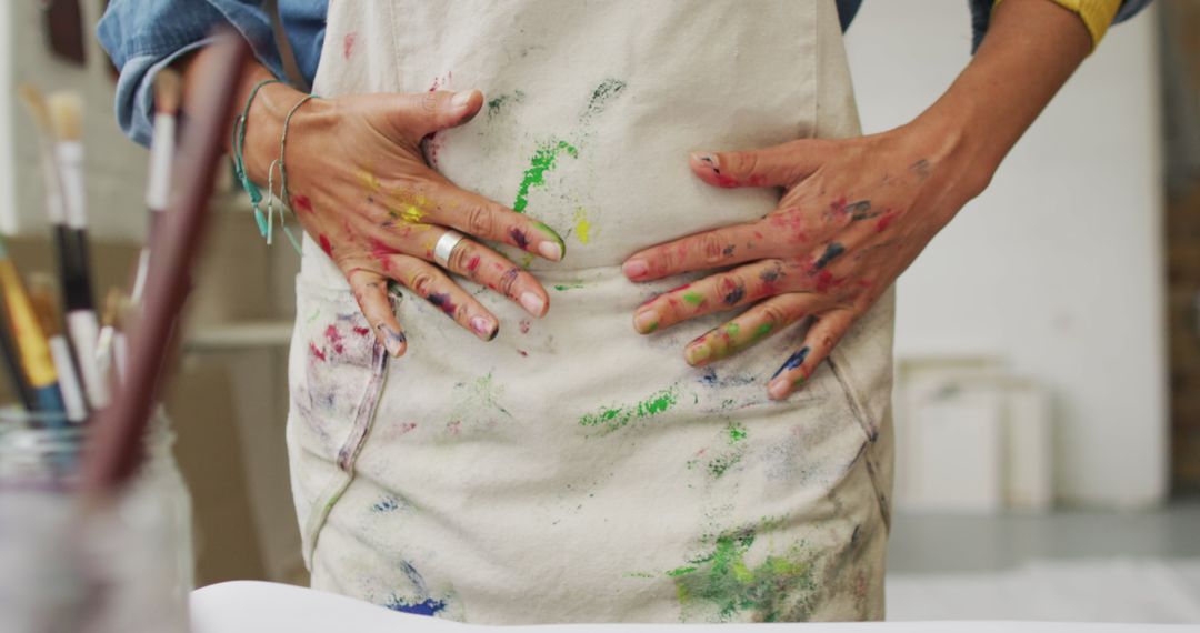 Artist Displaying Paint-Covered Hands in Creative Studio Environment