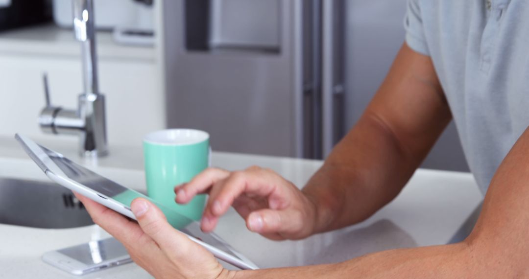 Person Using Tablet in Modern Kitchen with Coffee Mug - Free Images, Stock Photos and Pictures on Pikwizard.com