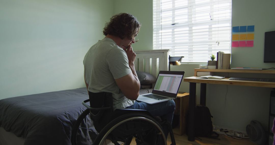 Young Man in Wheelchair Working on Laptop from Home Office - Free Images, Stock Photos and Pictures on Pikwizard.com