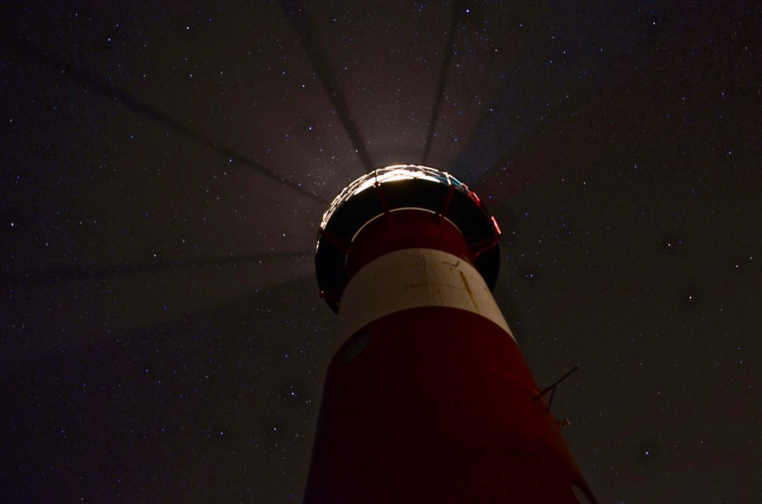 Low Angle of Illuminated Lighthouse at Night with Starry Sky - Free Images, Stock Photos and Pictures on Pikwizard.com