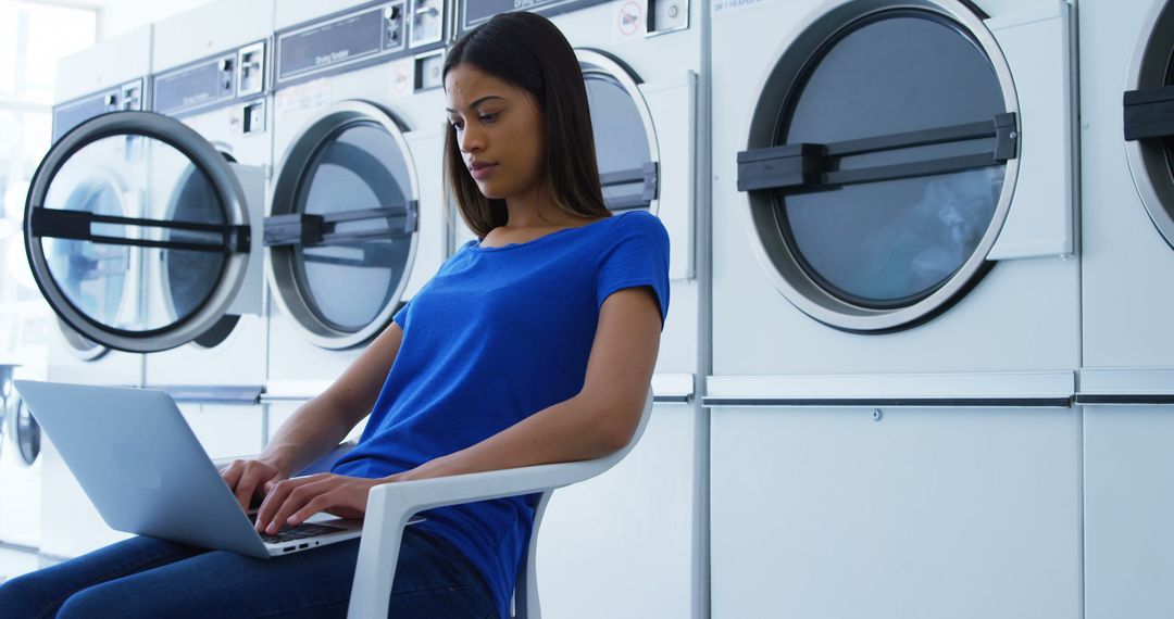 Young Woman Using Laptop in Laundromat - Free Images, Stock Photos and Pictures on Pikwizard.com