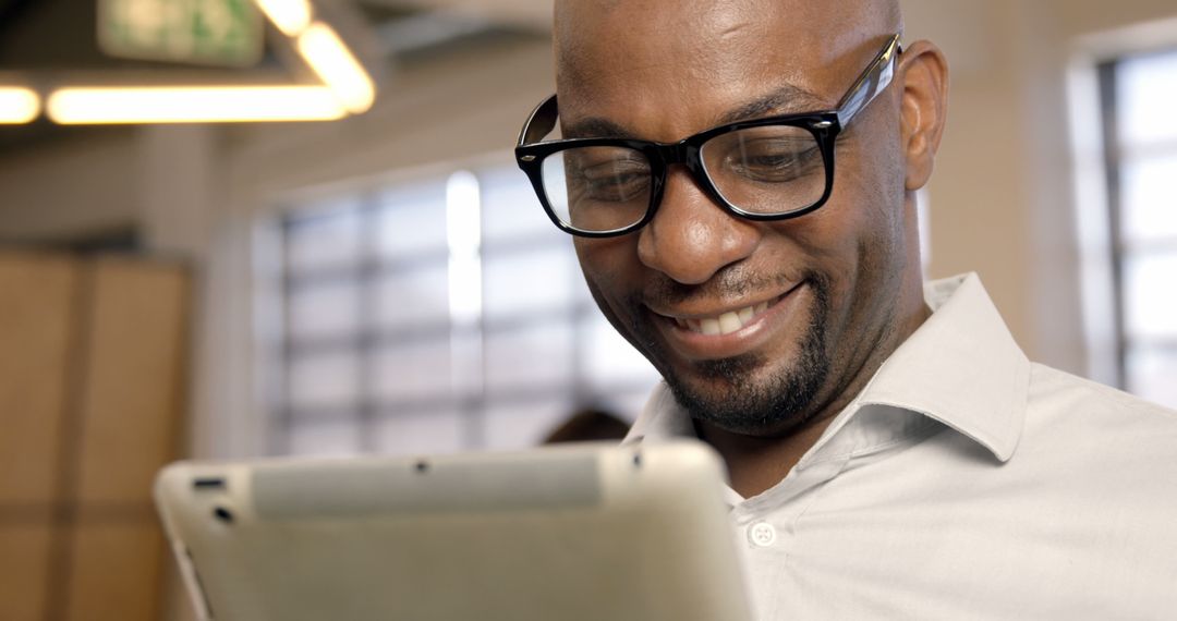 Smiling Man Wearing Glasses Using Digital Tablet in Modern Office - Free Images, Stock Photos and Pictures on Pikwizard.com