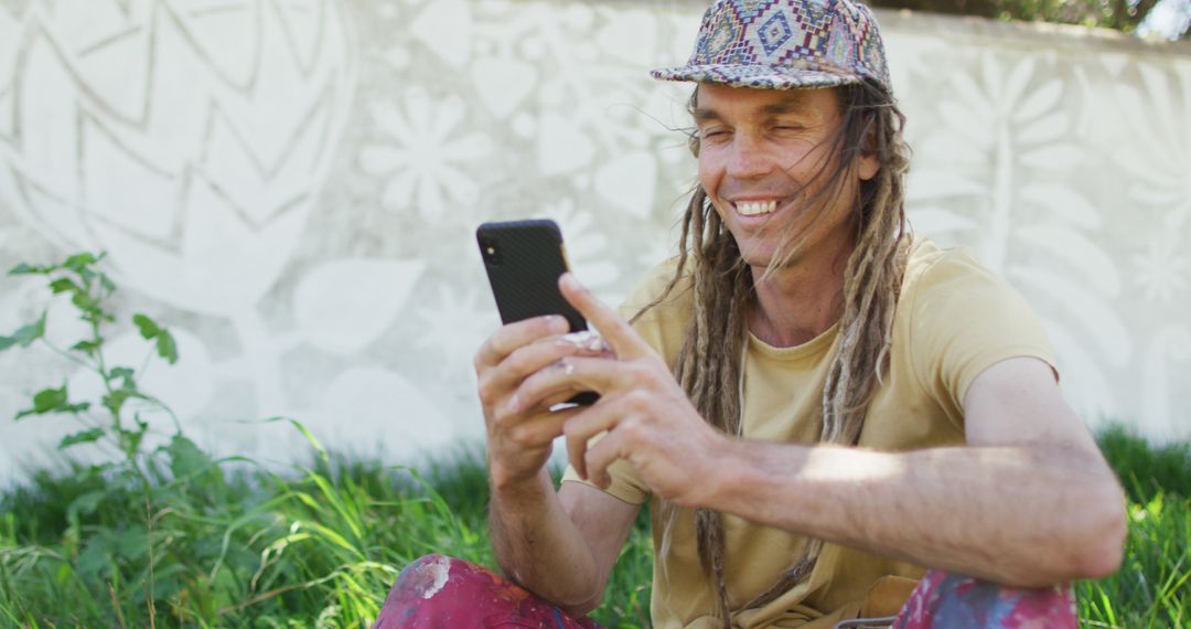 Man with Dreadlocks Enjoying Mobile Phone Outdoors - Free Images, Stock Photos and Pictures on Pikwizard.com