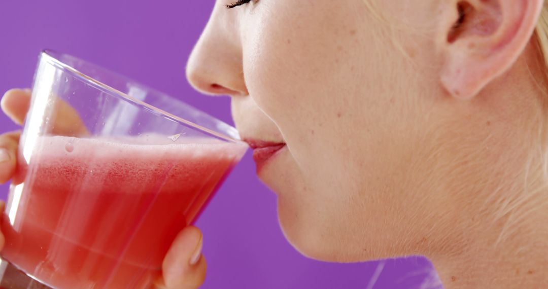 Woman Sipping Refreshing Pink Beverage with Relaxed Expression