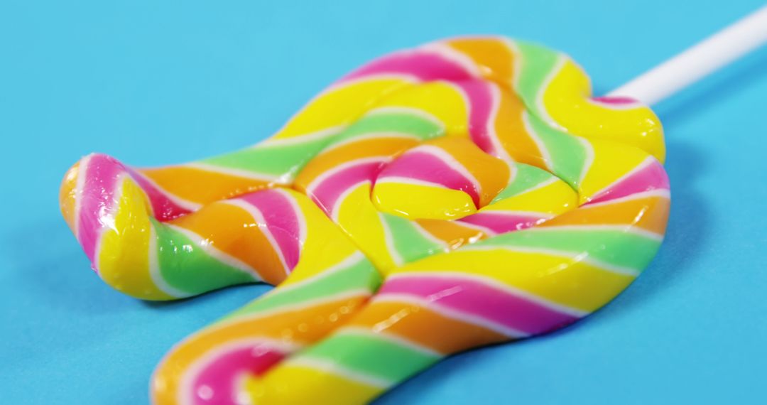 Close-Up of Colorful Swirled Lollipop Against Blue Background - Free Images, Stock Photos and Pictures on Pikwizard.com