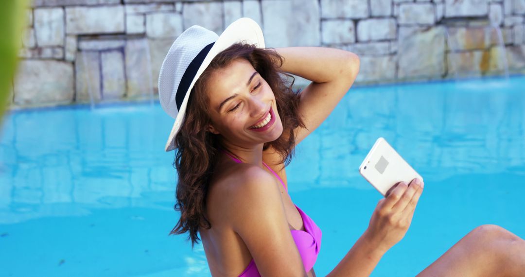 Smiling Woman Taking Selfie by Poolside in Sun Hat - Free Images, Stock Photos and Pictures on Pikwizard.com