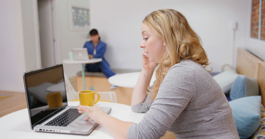 Woman Working on Laptop with Coffee Mug in Modern Office Space - Free Images, Stock Photos and Pictures on Pikwizard.com