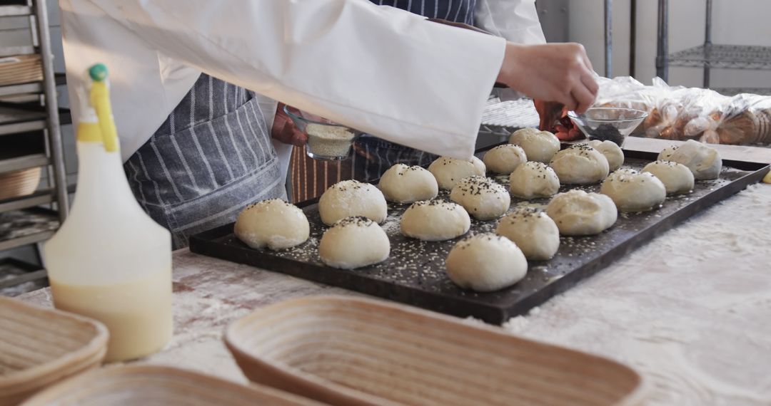 Baker Sprinkling Seeds on Fresh Dough Balls in Bakery - Free Images, Stock Photos and Pictures on Pikwizard.com