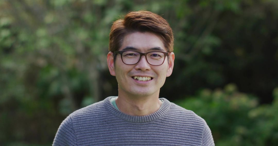 Smiling Man with Glasses Relaxing in Natural Garden Environment