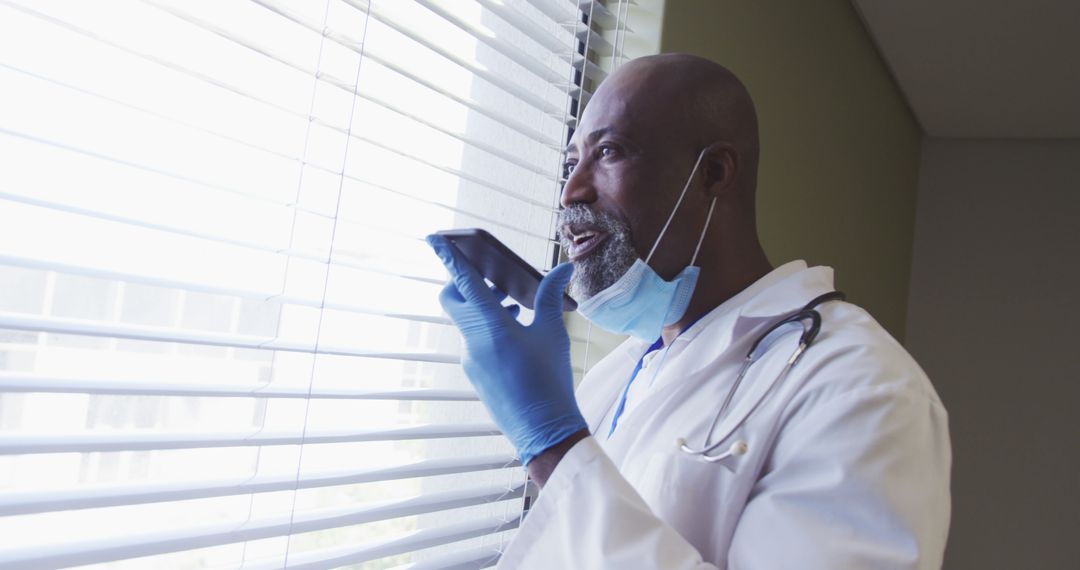 Doctor with Mask Using Smartphone by Window - Free Images, Stock Photos and Pictures on Pikwizard.com