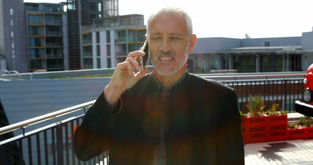 Businessman Talking on Smartphone on Rooftop with Modern Buildings Background - Free Images, Stock Photos and Pictures on Pikwizard.com