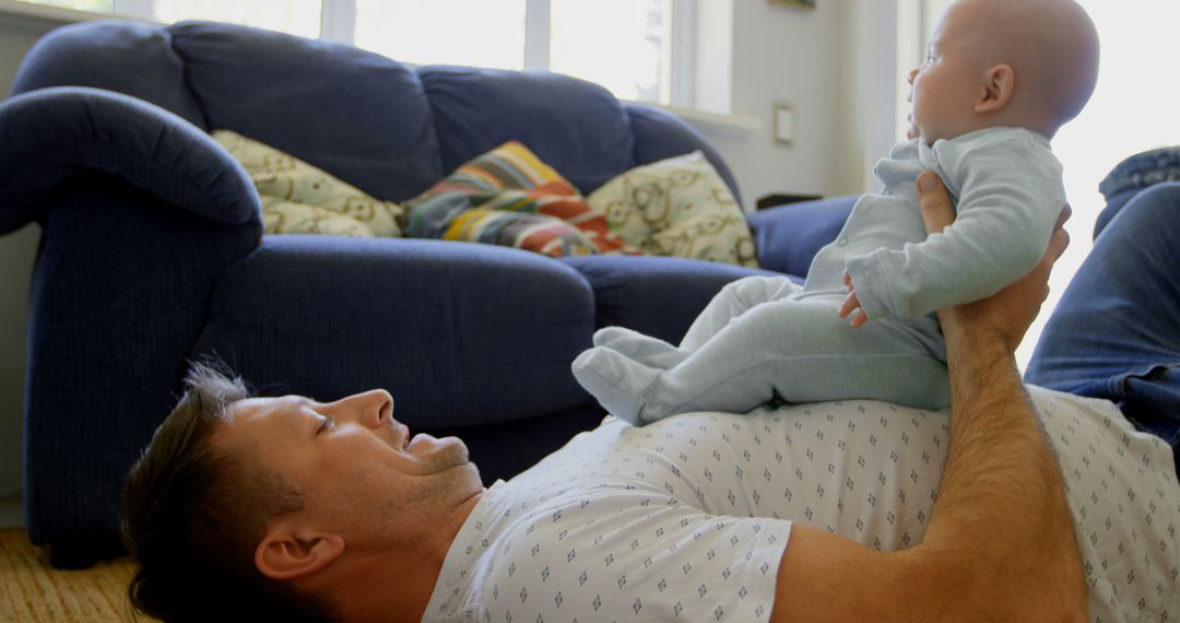 Father Lifting Infant in Cozy Living Room - Free Images, Stock Photos and Pictures on Pikwizard.com