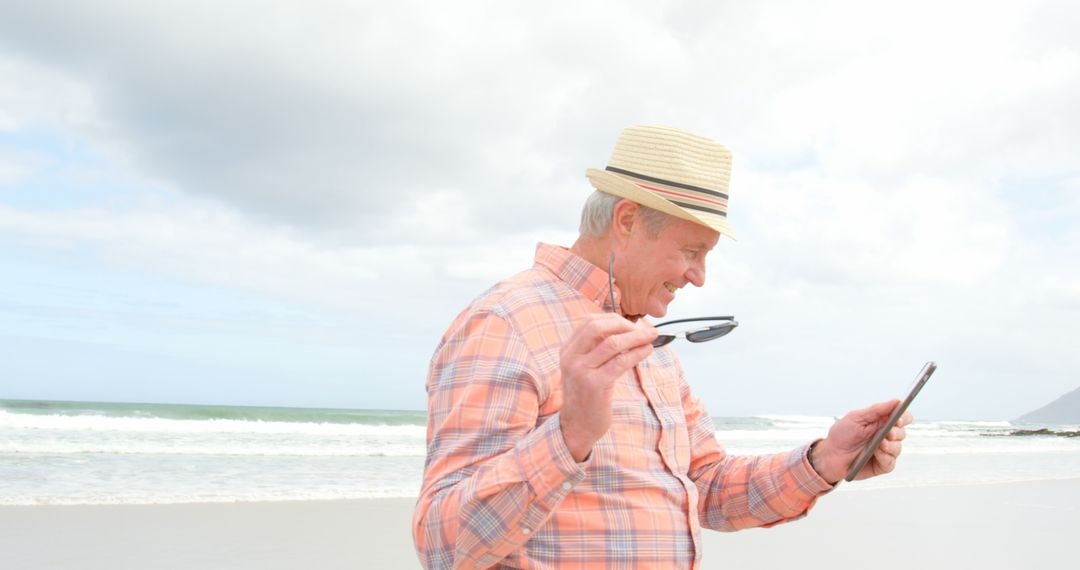 Senior Man Enjoying Beach with Digital Tablet and Sunglasses - Free Images, Stock Photos and Pictures on Pikwizard.com