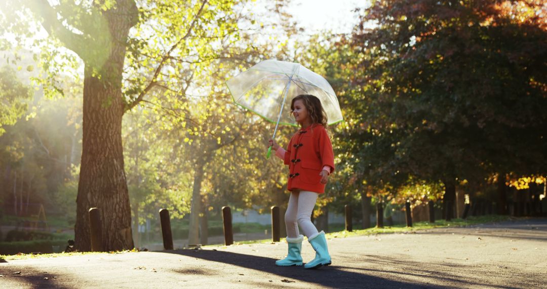 Young Girl Walking with Umbrella on Sunny Autumn Day - Free Images, Stock Photos and Pictures on Pikwizard.com