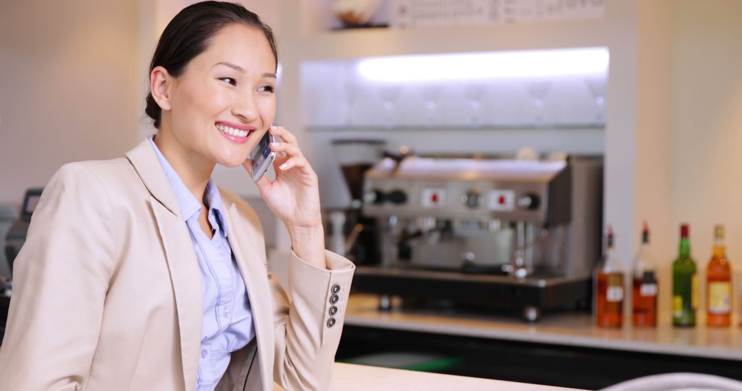 Smiling Businesswoman Talking on Phone at Bar Counter