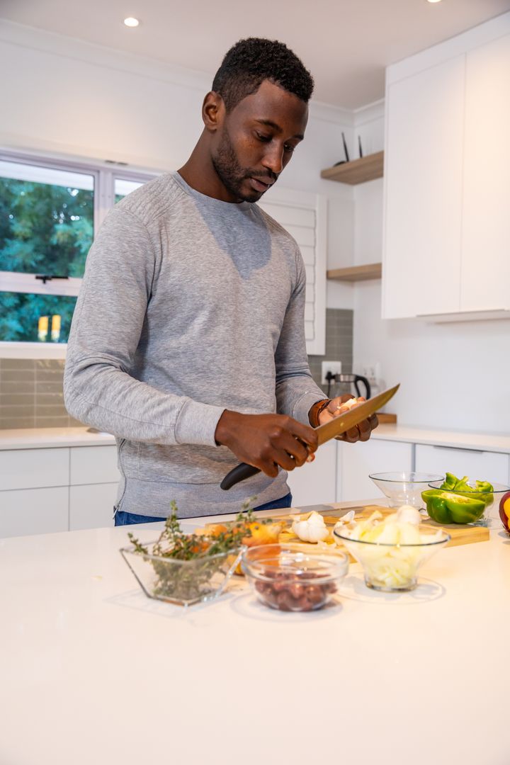 Man Slcing Onion in Modern Kitchen Styled with Healthy Ingredients