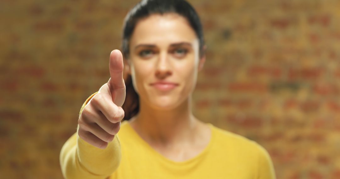 Woman Giving Thumbs Up Gesture Against Brick Wall - Free Images, Stock Photos and Pictures on Pikwizard.com