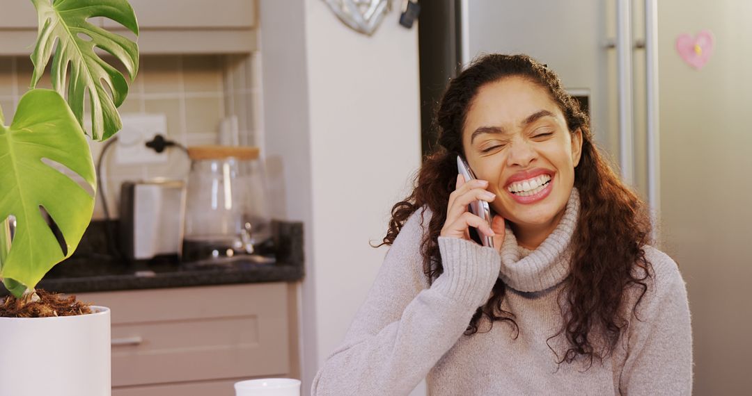 Woman Joyfully Talking on Phone Sitting in Kitchen - Free Images, Stock Photos and Pictures on Pikwizard.com