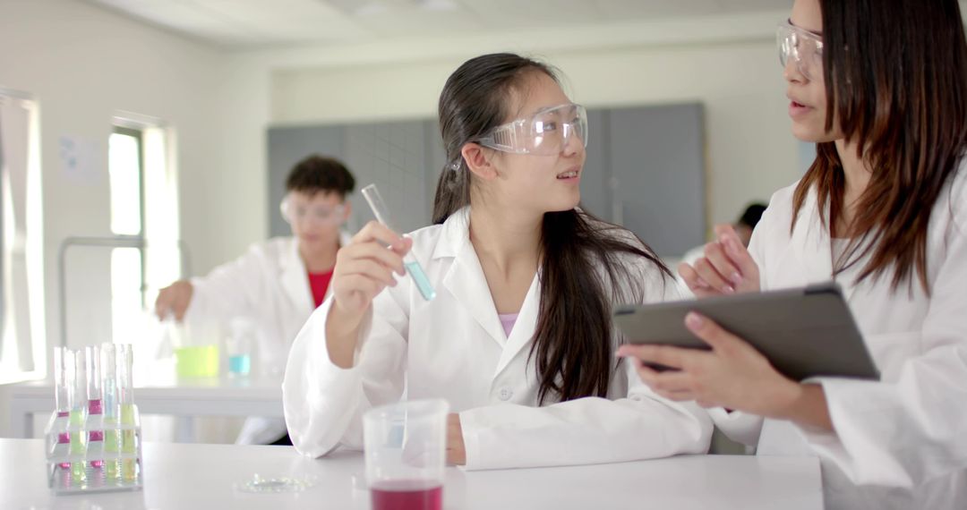 Chinese student conducting chemistry experiment with tablet in modern science classroom