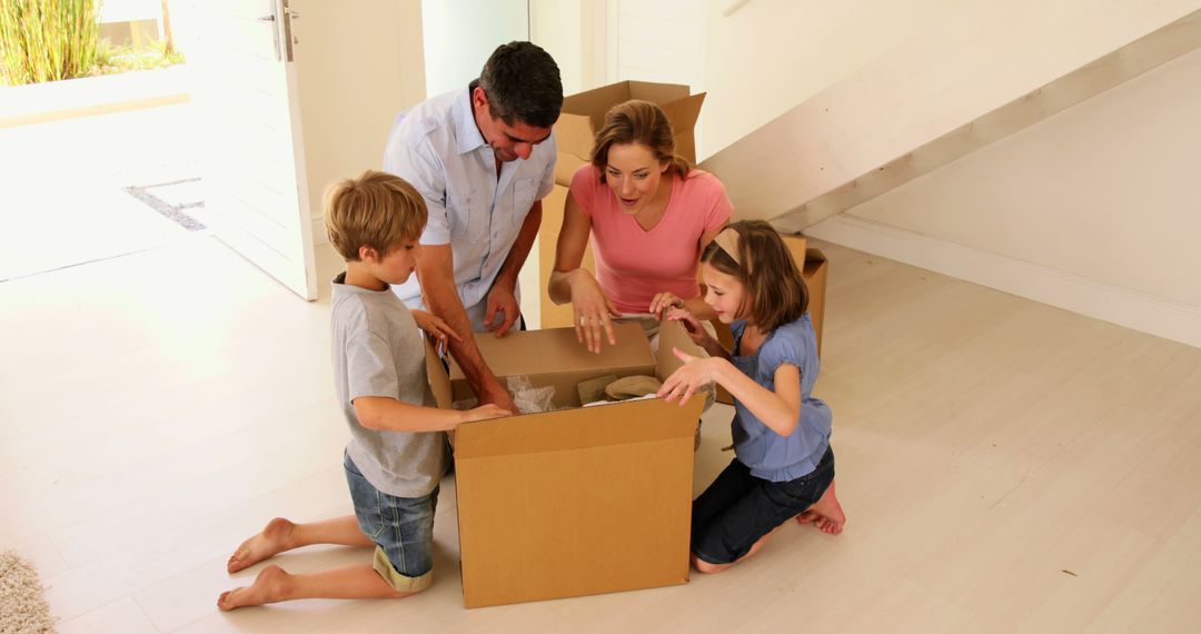 Happy Family Opening Box in New Home During Moving Day - Free Images, Stock Photos and Pictures on Pikwizard.com