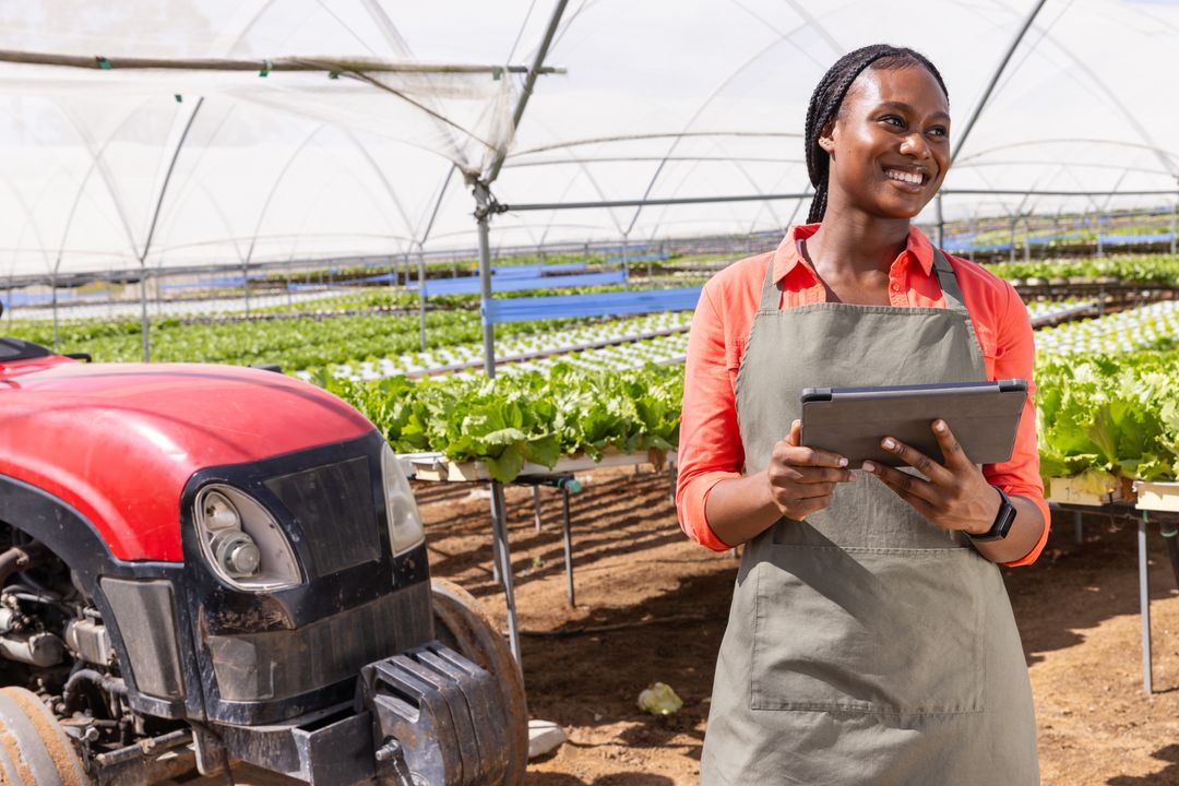 Woman with Tablet Inspecting Lettuce in Greenhouse Near Tractor