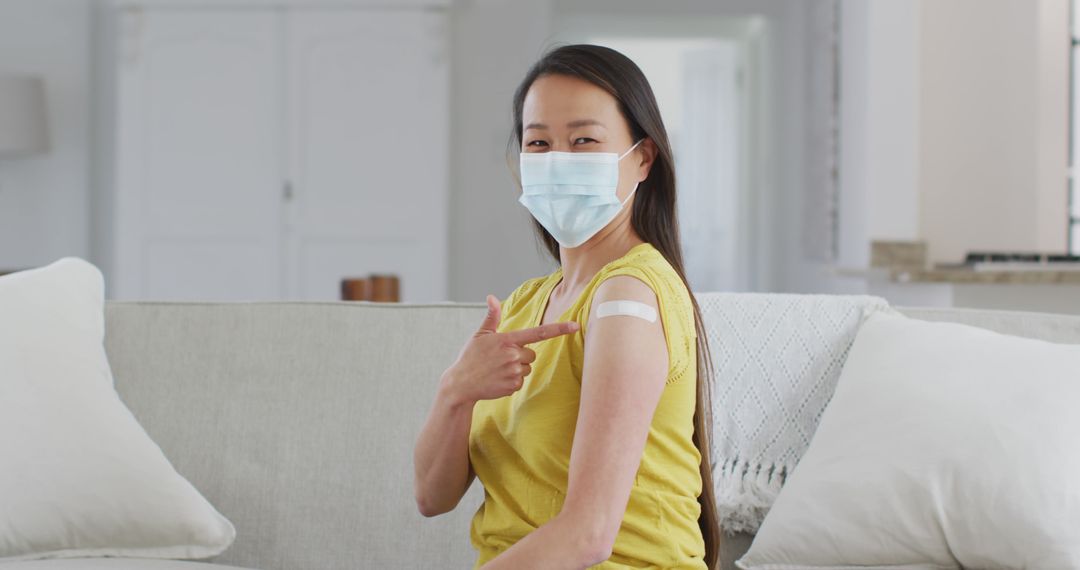 Woman Showing Vaccination Band-Aid Wearing Mask On Sofa - Free Images, Stock Photos and Pictures on Pikwizard.com