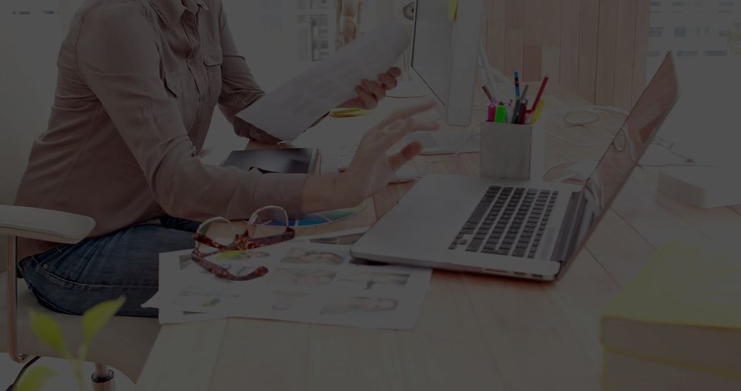Professional Woman Utilizing Laptop and Analyzing Documents in Modern Office