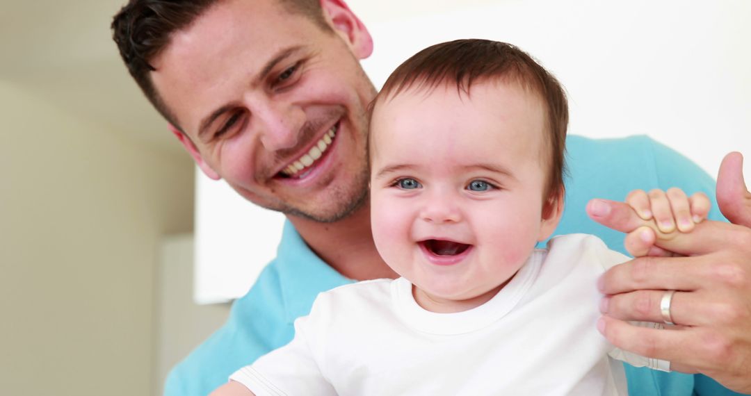 Joyful Father Supporting Baby Son's First Steps in Kitchen