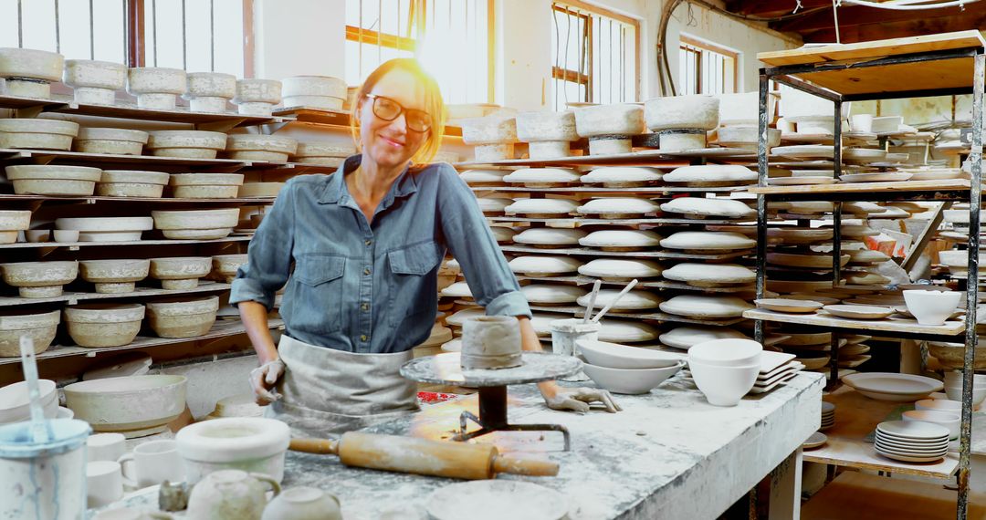 Female Potter in Studio Smiling Confidently with Pottery Wheel and Finished Ceramics - Free Images, Stock Photos and Pictures on Pikwizard.com