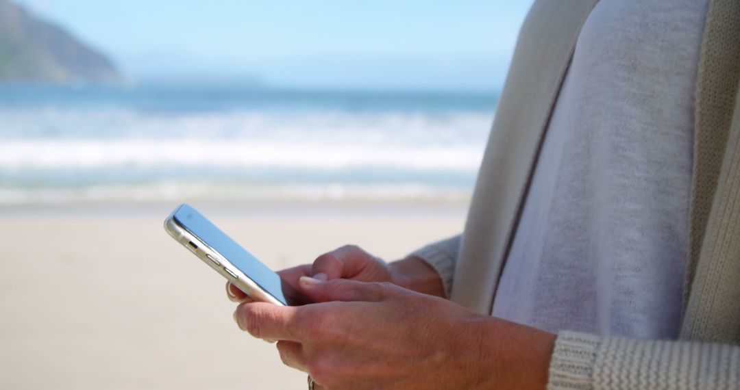 Person Sending Text Message by Ocean on Summer Day - Free Images, Stock Photos and Pictures on Pikwizard.com