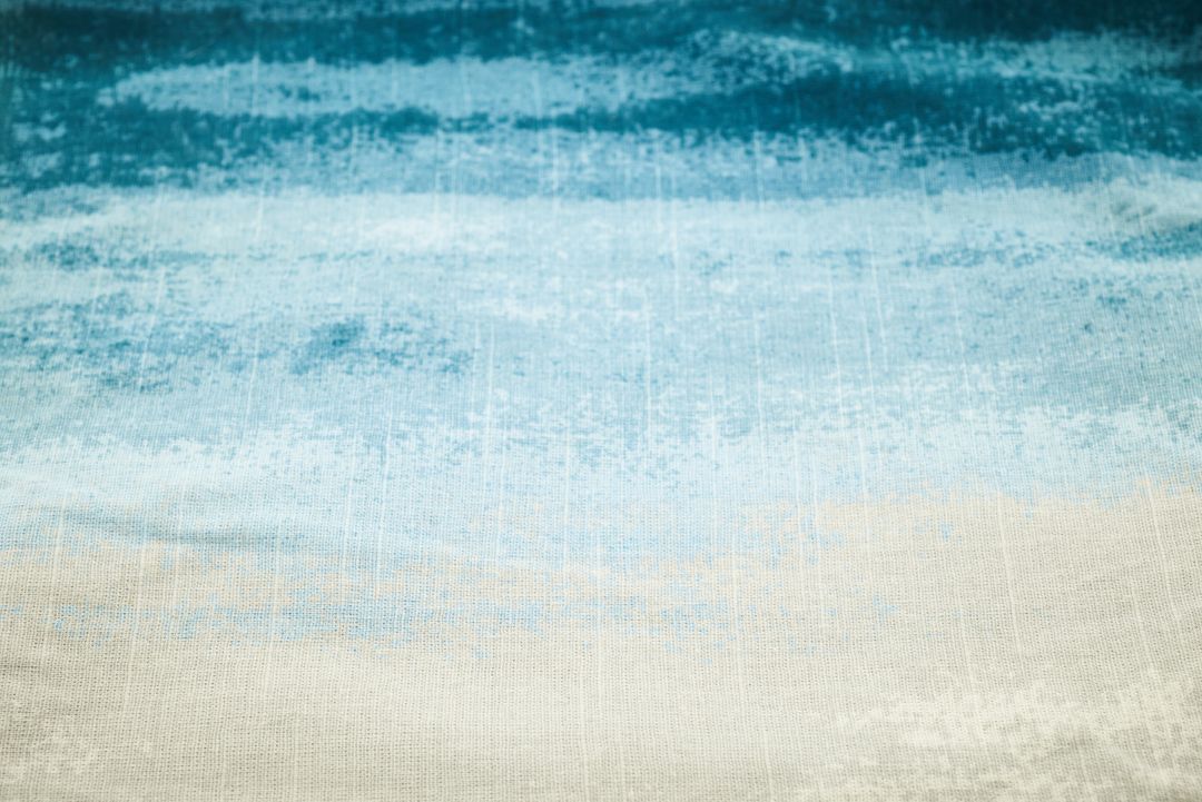 Abstract blue watercolor fabric texture evoking ocean waves and sandy shore gradient