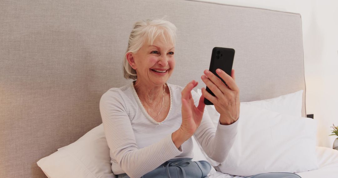 Senior Woman Using Smartphone Smiling on Comfortable Bed