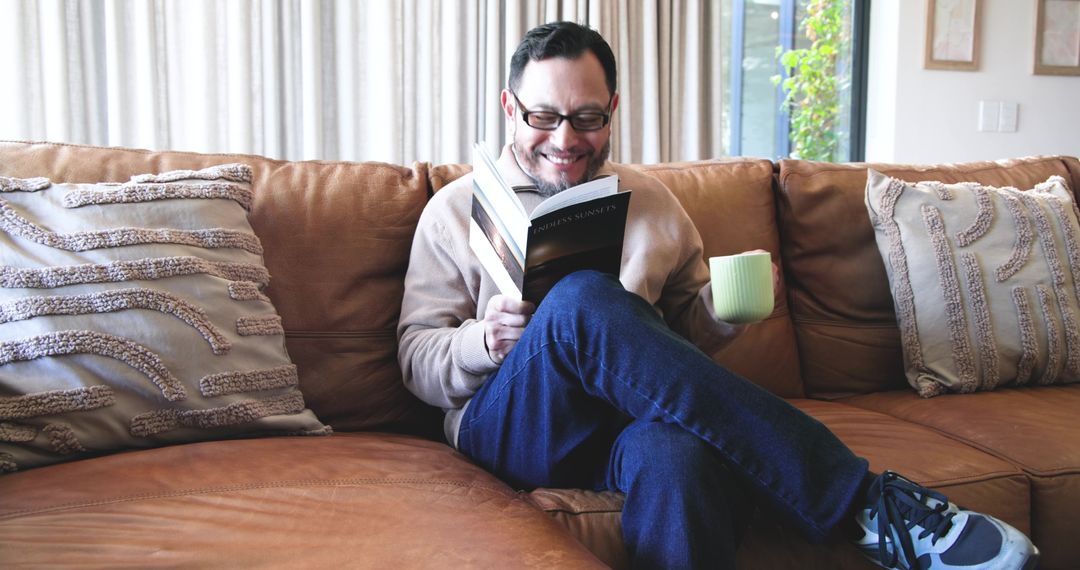 Man Relaxing on Leather Couch Reading Book with Coffee Mug