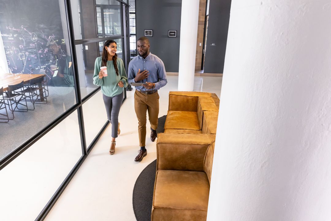 Diverse Coworkers Walking and Conversing Inside Modern Office