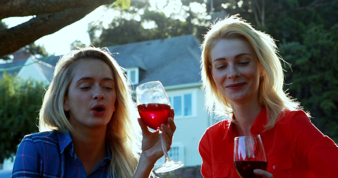 Two Women Enjoying Red Wine Outdoors on Sunny Day - Free Images, Stock Photos and Pictures on Pikwizard.com