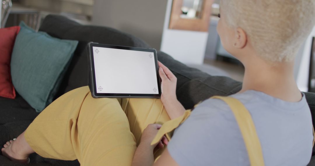 Person Relaxing Indoors Holding Tablet on Couch - Free Images, Stock Photos and Pictures on Pikwizard.com