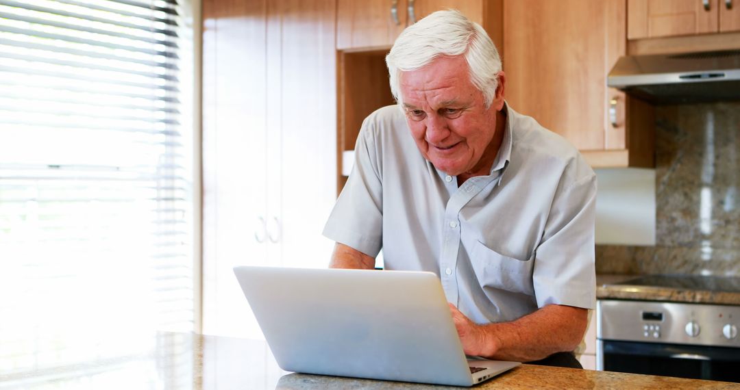 Senior Man Using Laptop in Modern Home Kitchen - Free Images, Stock Photos and Pictures on Pikwizard.com