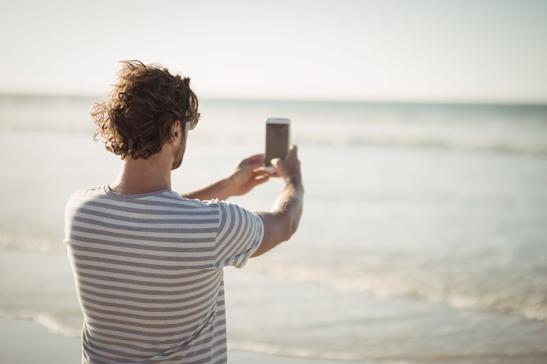 Man Taking Photo of Sea on Sunny Beach Day - Free Images, Stock Photos and Pictures on Pikwizard.com